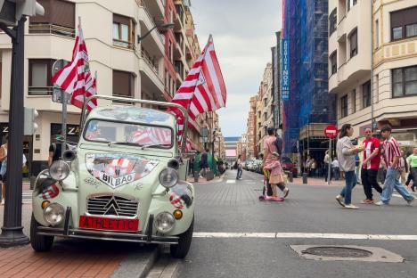 Car decorated with Athletic Bilbao flags and imagery parked on a city street.