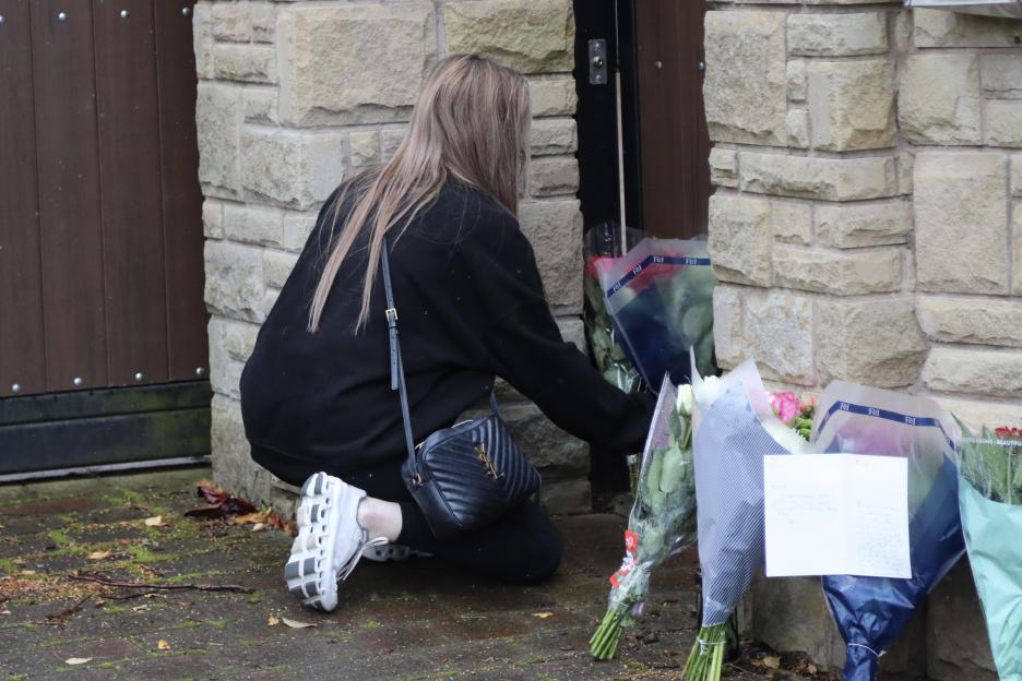 A woman placing flowers at a memorial.