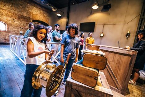 Children interacting with a ship's telegraph at a Titanic exhibition.