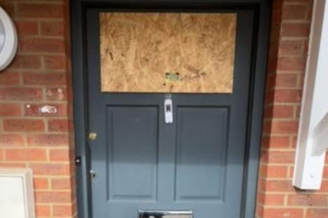 Boarded-up front door after a home attack.