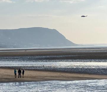 Coastguard helicopter searching a beach.