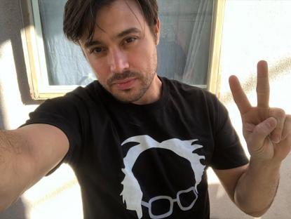 Selfie of a man wearing a Bernie Sanders t-shirt and giving a peace sign.