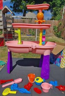 Pink water table with assorted colorful toys.