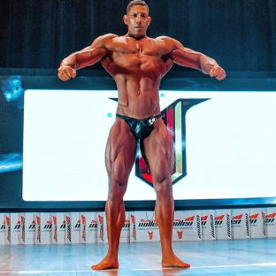 Bodybuilder Guilherme Henrique posing on stage.