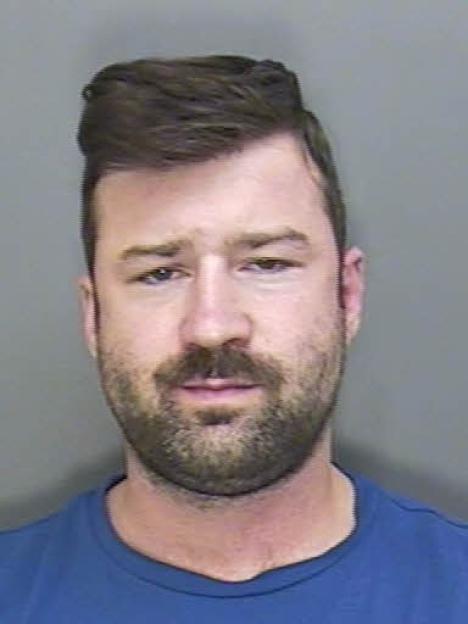 Mugshot of a man with dark hair and a beard, wearing a blue shirt.