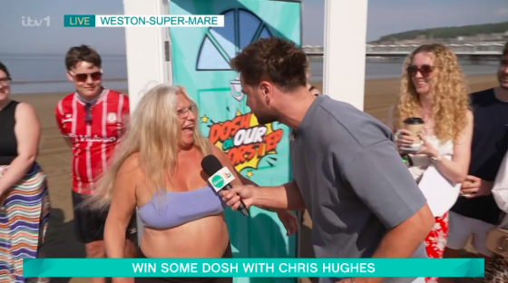 Chris Hughes interviewing a woman on a beach for a game show.