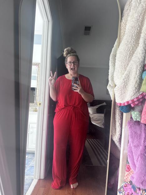 Woman in red pajamas taking a selfie in a mirror.