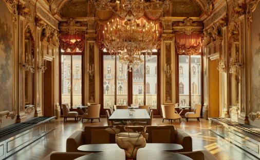 Ornate dining room in Aman Venice with large windows overlooking the city.