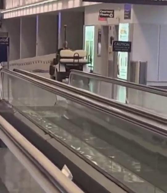 Golf cart on moving walkway in airport terminal.
