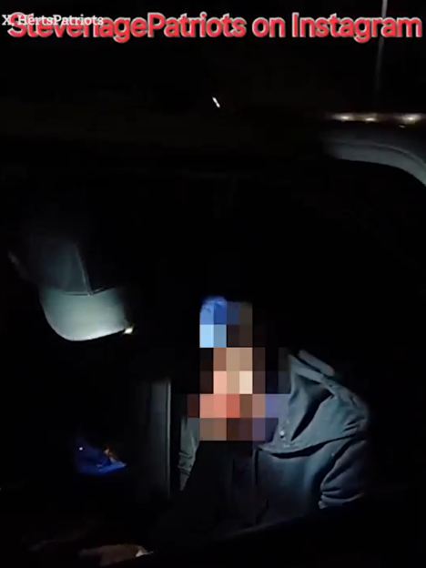 Screenshot of a person in a car at night, face obscured.