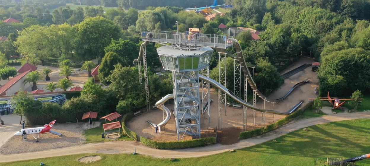 Adventure park featuring a tall slide tower and an airplane-themed playground.