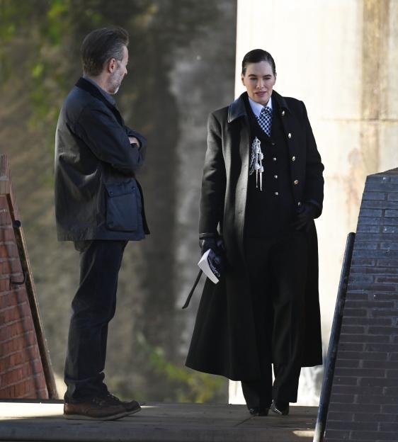 Lena Headey in a black coat and a man in a black jacket.