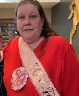 Woman wearing a red shirt and a 50th birthday sash.