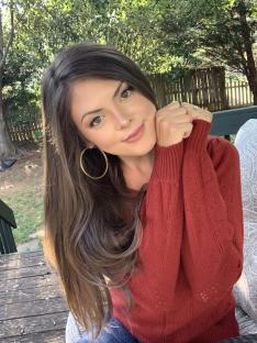 Woman with long brown hair wearing a red sweater.