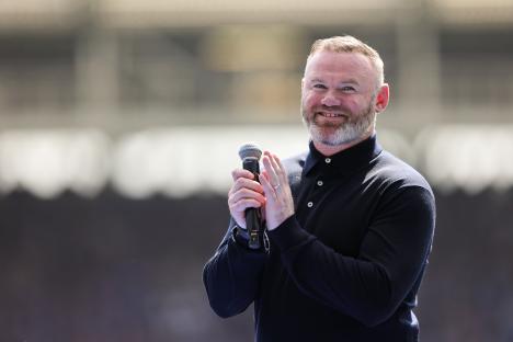 Wayne Rooney speaking into a microphone and applauding.