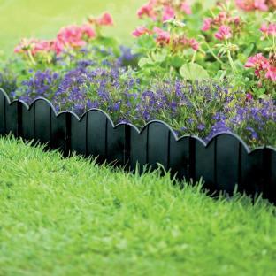 Black plastic garden edging installed in a flowerbed.