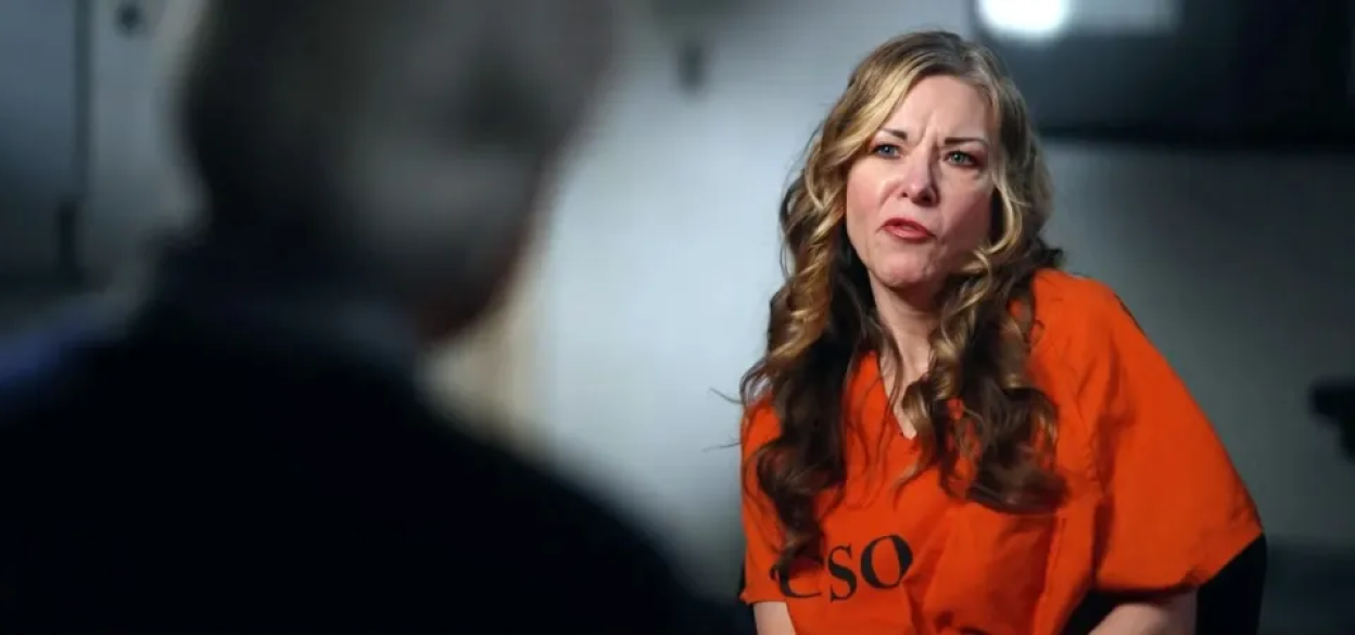 Woman in orange jumpsuit being interviewed.