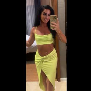 Woman in a lime green two-piece outfit taking a selfie.