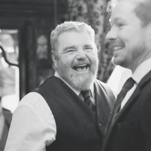Black and white photo of two men, one laughing.