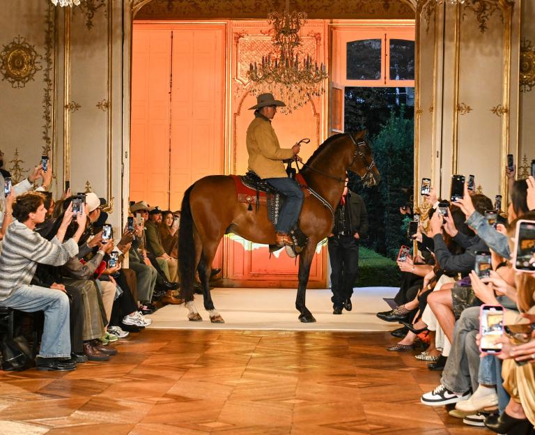 A model on horseback walks a runway at Paris Fashion Week.