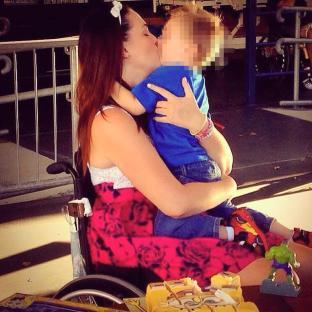 Woman in wheelchair kissing child.