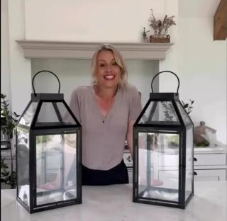 Woman standing between two large black lanterns.