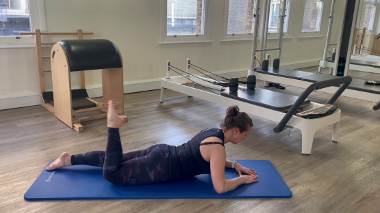 Woman performing a Pilates leg exercise.