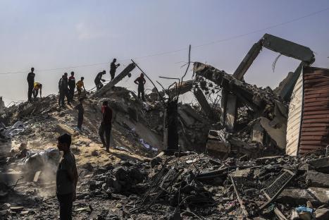 Destruction and people surveying the damage of a bombed-out building.