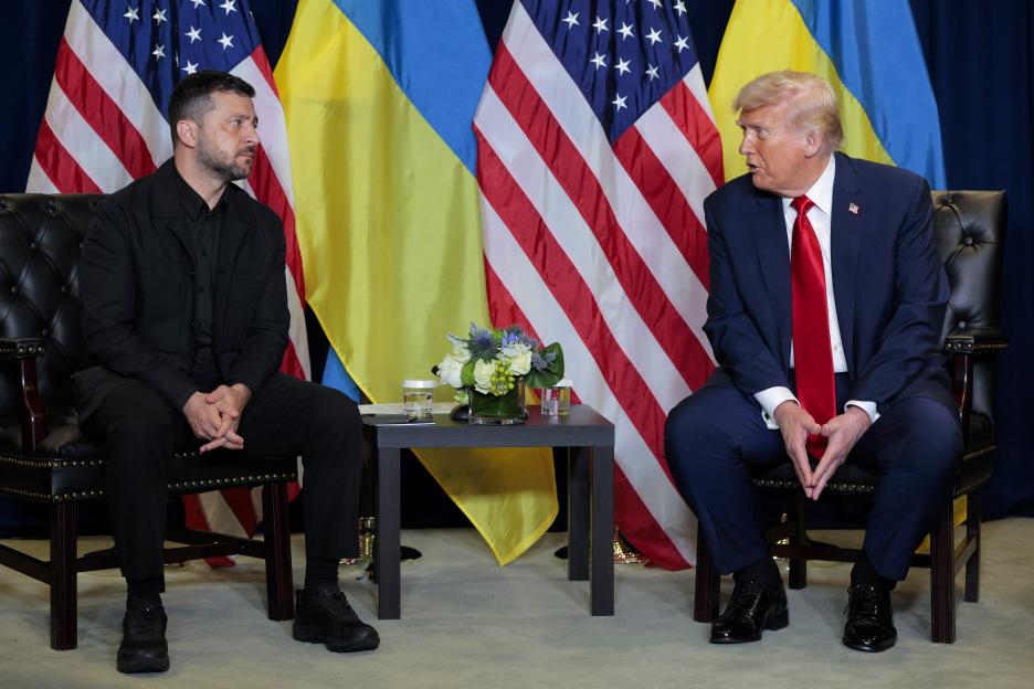 U.S. President Donald Trump and Ukrainian President Volodymyr Zelensky sitting across from each other with US and Ukrainian flags in the background.