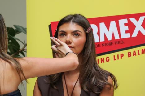 A woman having her makeup applied at a Carmex event.
