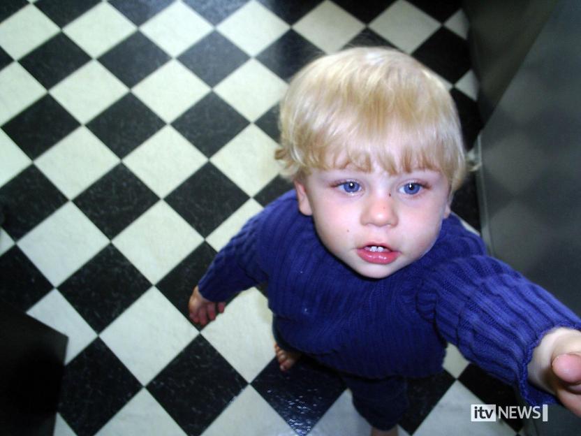 Baby Peter Connelly, wearing a blue jumper, looks up at the camera.