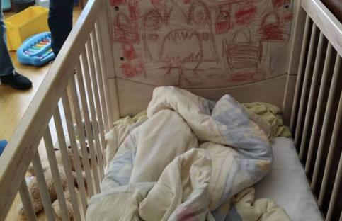 Child's cot with children's drawings on the headboard.