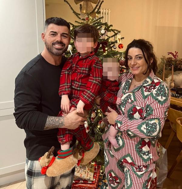 Anthony Hutton, his partner, and their two children in matching Christmas pajamas by a Christmas tree.