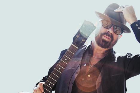Dave Stewart holding a guitar, announcing a new album.
