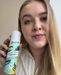 Woman holding a can of Batiste dry shampoo.