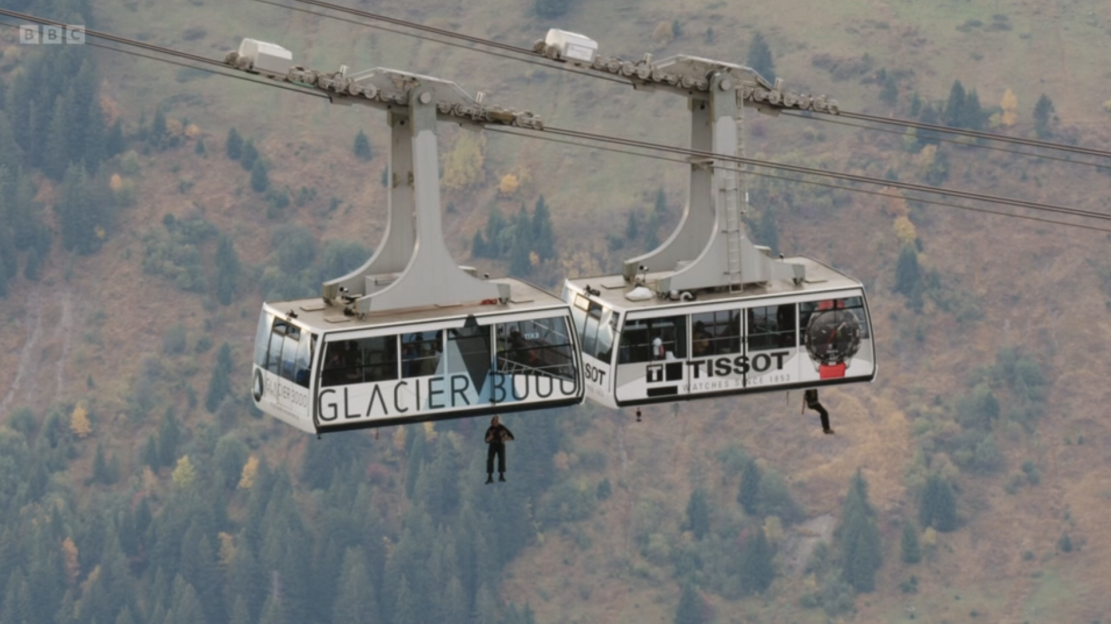 Two cable cars with people BASE jumping.