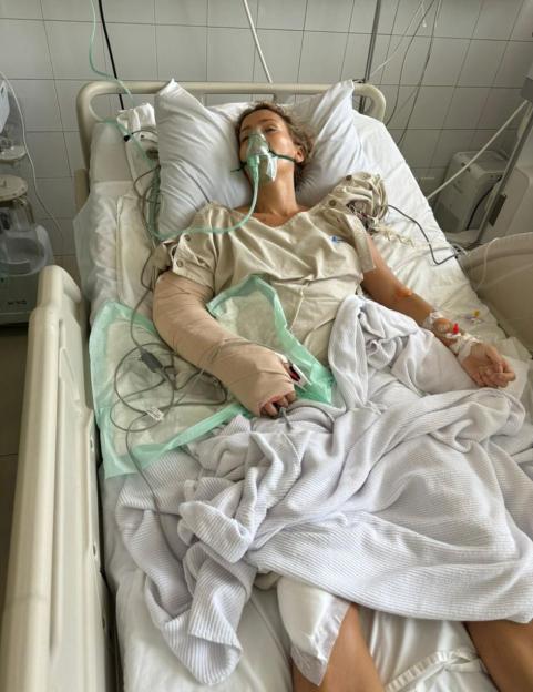 Woman in hospital bed with arm injury.
