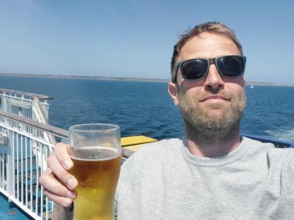 Man on a ferry holding a beer.