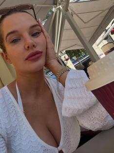 Woman in white sweater holding a coffee cup.