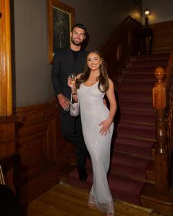 Couple posing on a staircase; the woman wears a sparkly white dress.