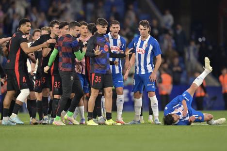 Soccer players arguing after a player falls to the ground.