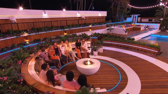 Islanders gathered around a fire pit at night.