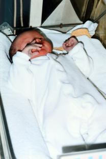 Newborn baby girl in white onesie.