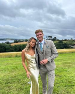 Couple in formal wear standing in a field.