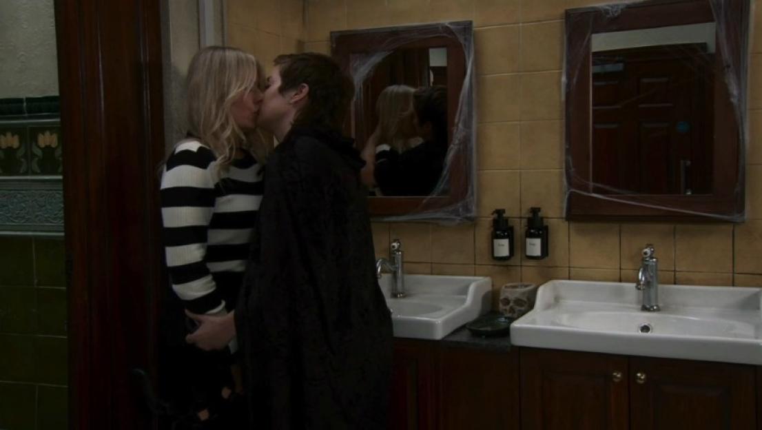 Two former partners kissing in a bathroom decorated for Halloween.