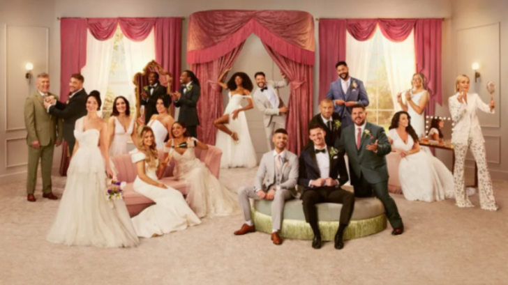 A group of men in suits and women in wedding dresses posing for a picture.