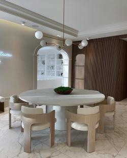 Dining room with round table and light-colored chairs.