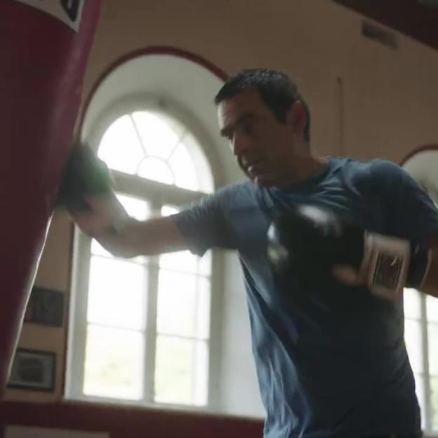 Ronnie O'Sullivan training in a boxing ring, punching a red bag.