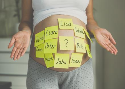 Pregnant woman's belly with sticky notes of baby names on it.
