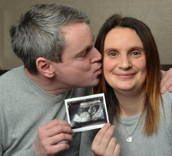 Couple holding ultrasound image of their unborn baby.